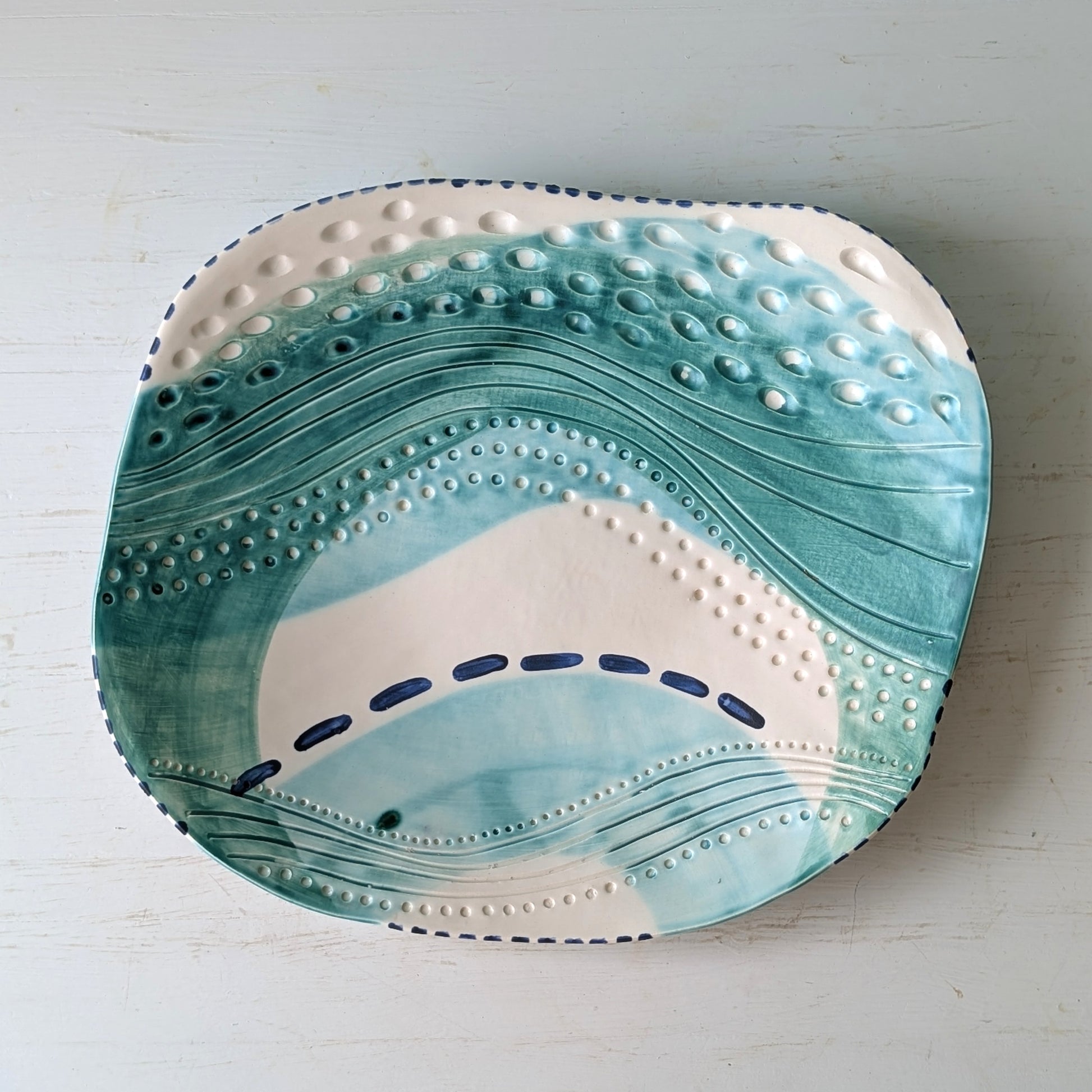 Ceramic platter with wavy blue and white design on a light gray background