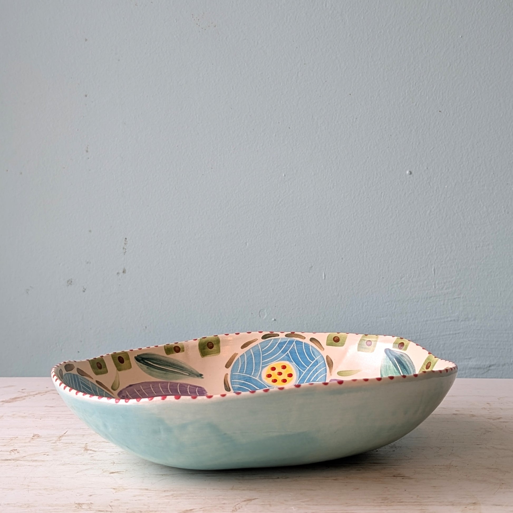 Decorative ceramic bowl with floral pattern on a wooden surface and light grey background