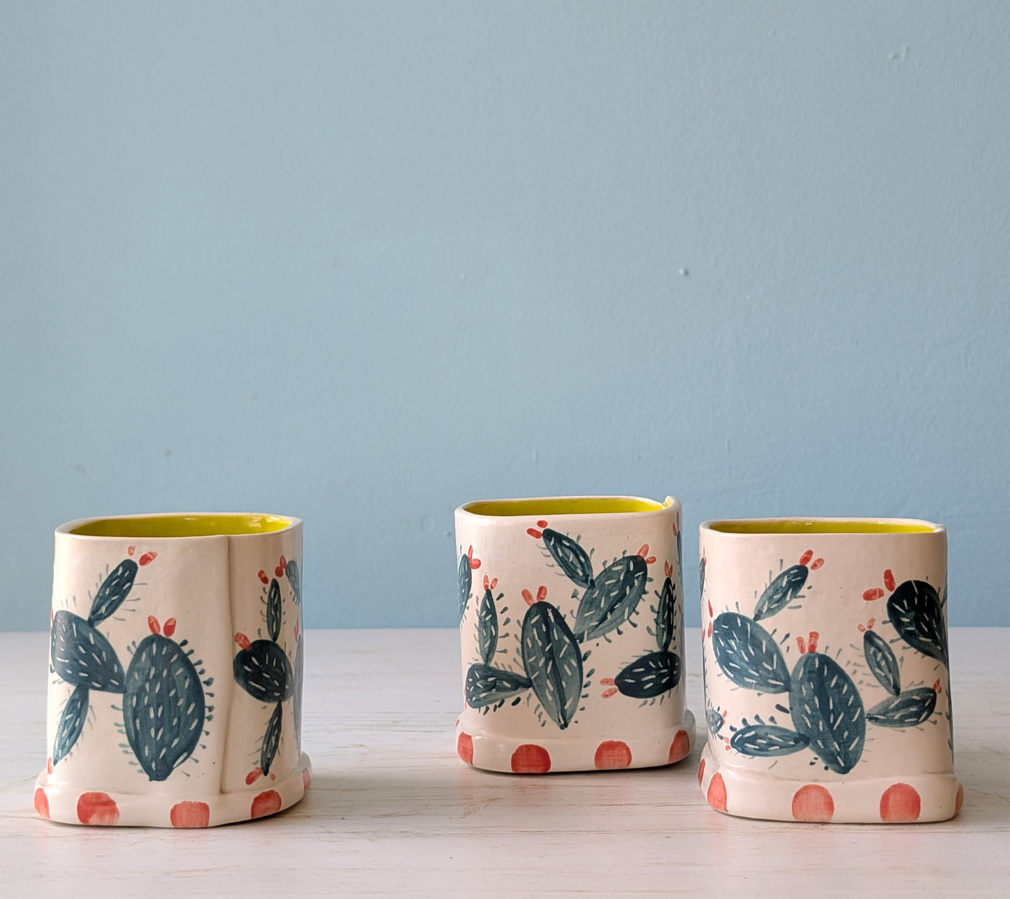 Three ceramic vases with cactus design on a light blue background