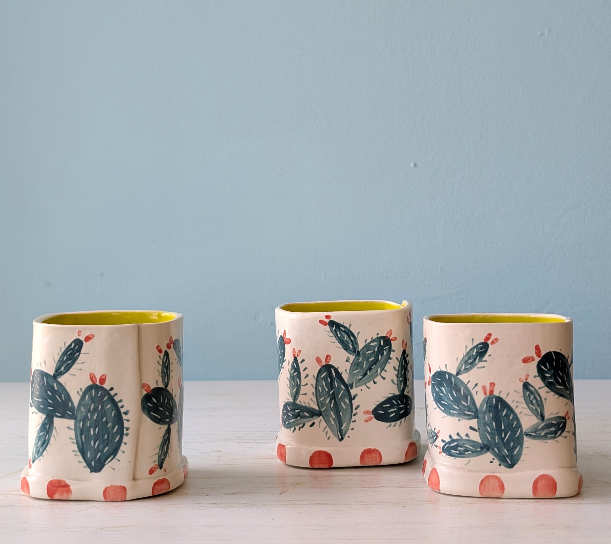 Three ceramic vases with cactus design on a light blue background