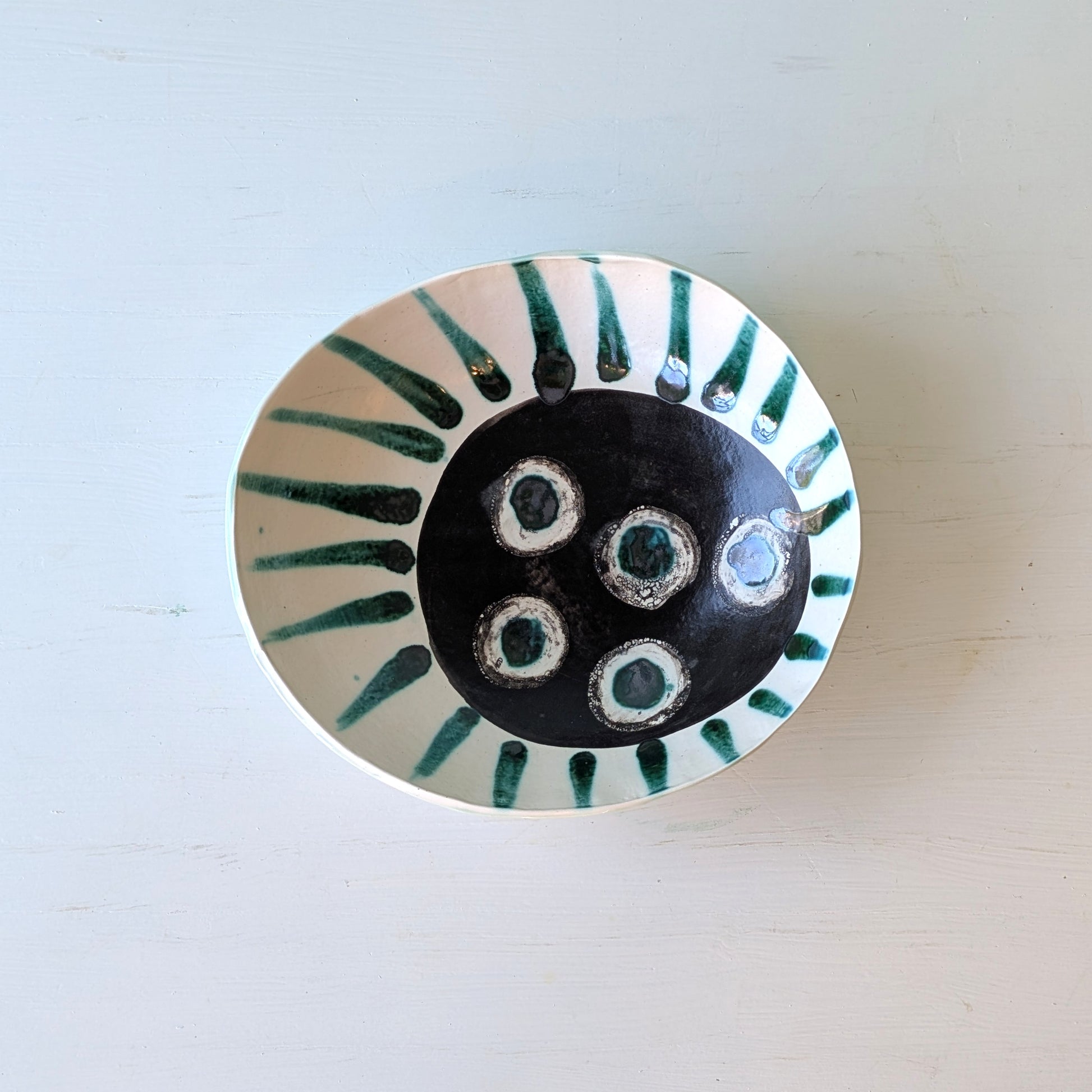 Ceramic plate with black center and green accents on a light background
