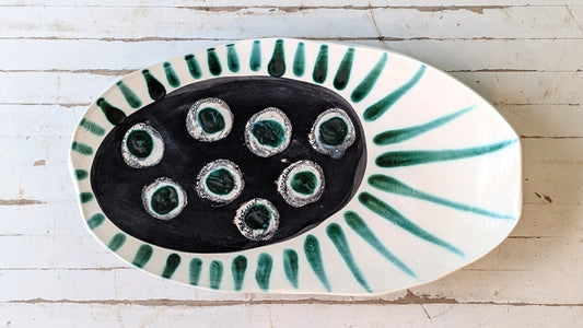 Top view of a white ceramic platter with green abstract design.