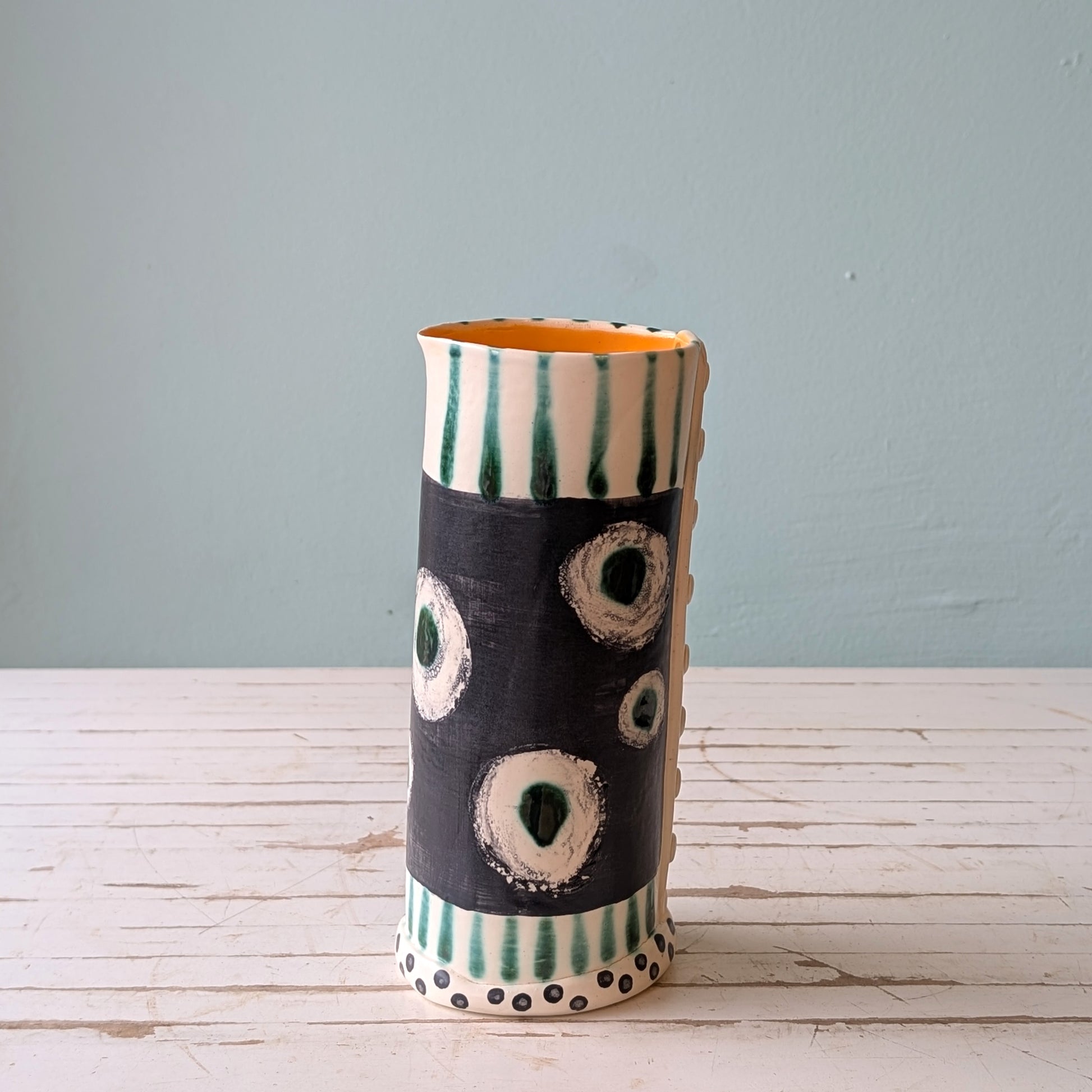 Ceramic vase with abstract design on a wooden surface and light blue background