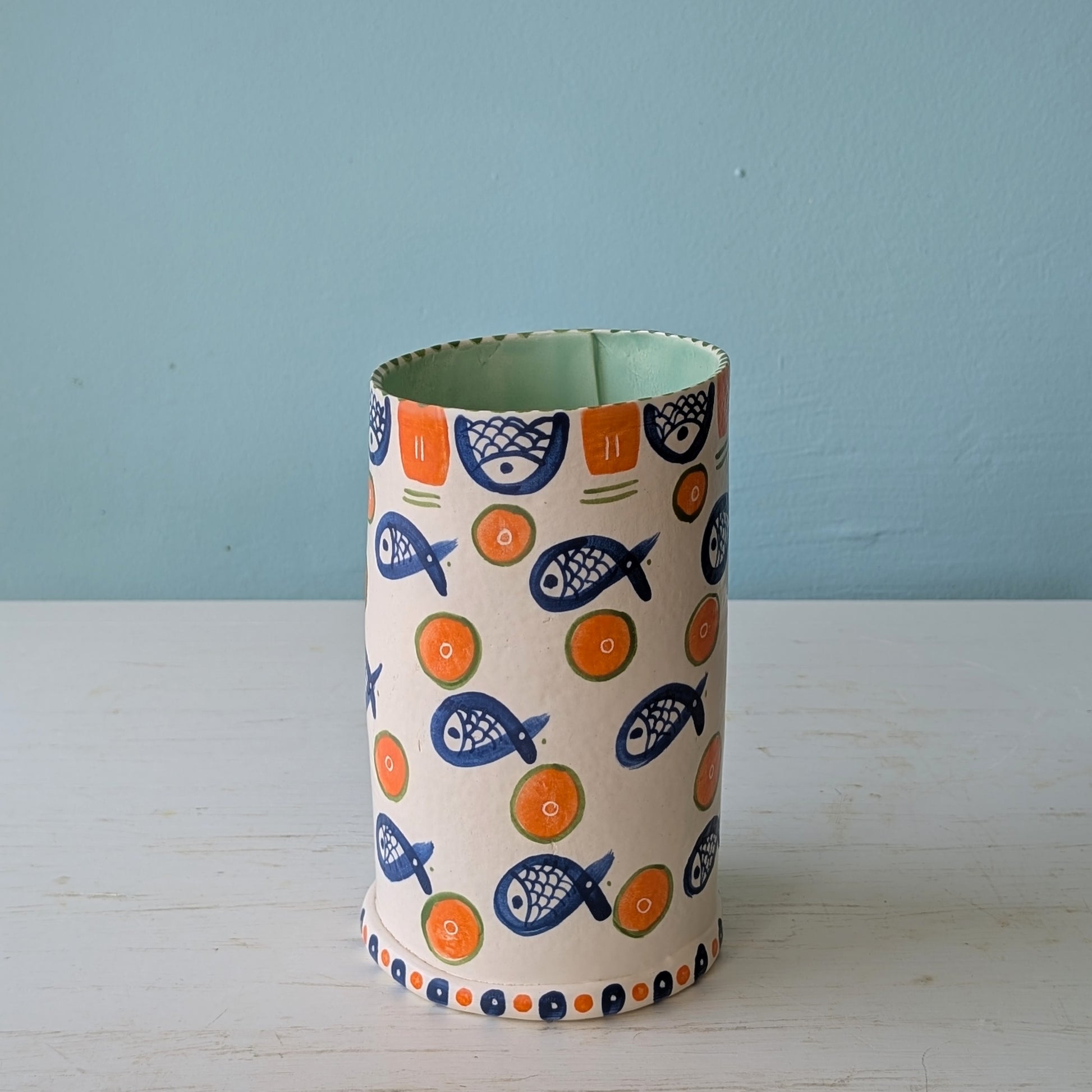 Cylindrical vase with fish pattern on a light blue background