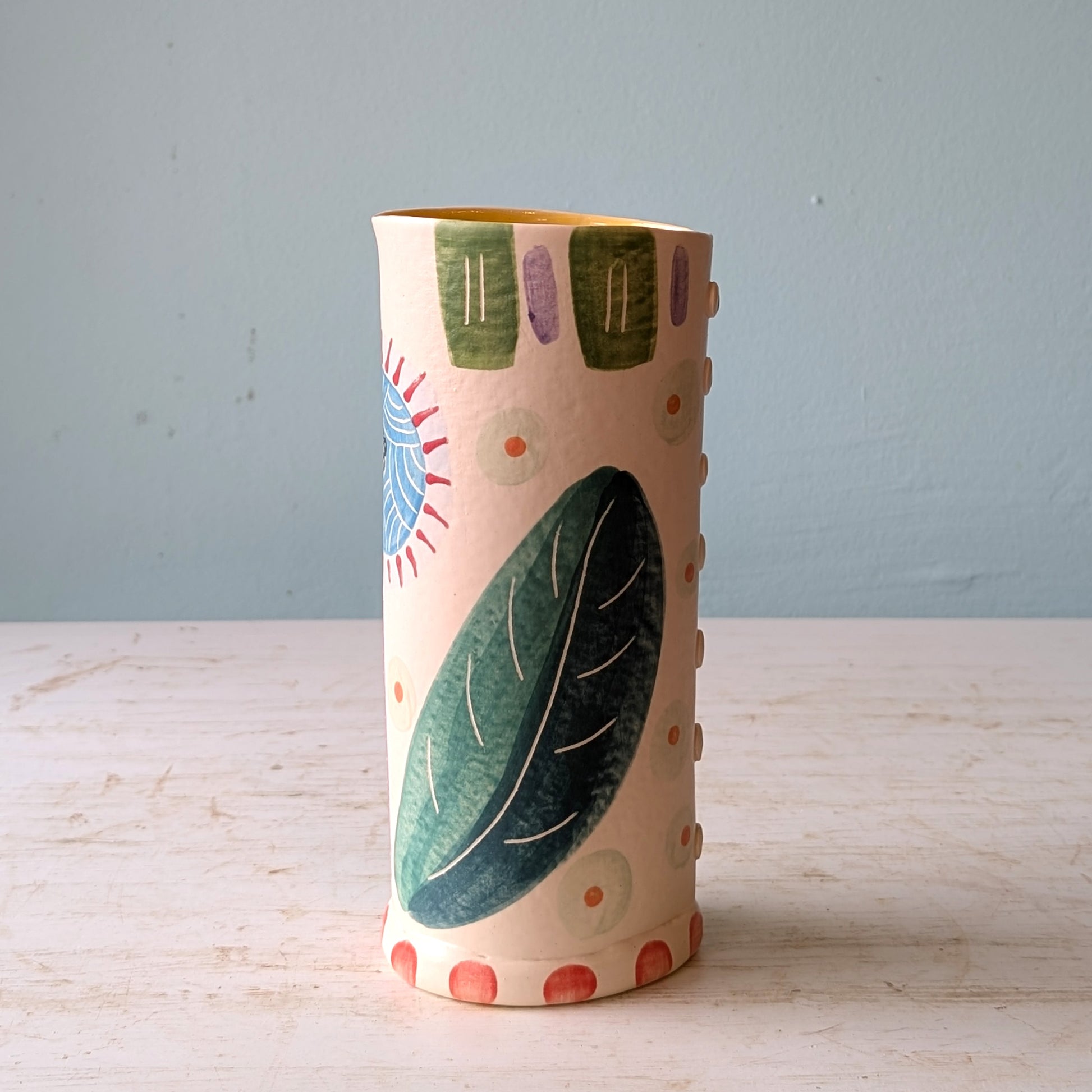 Decorative ceramic vase with floral patterns on a wooden surface and light blue background