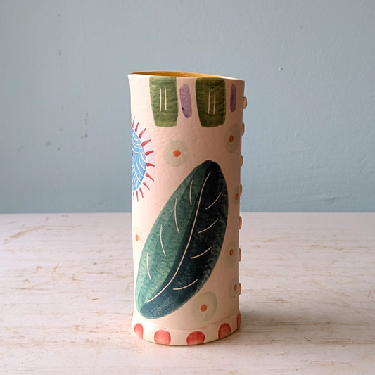 Decorative ceramic vase with floral patterns on a wooden surface and light blue background