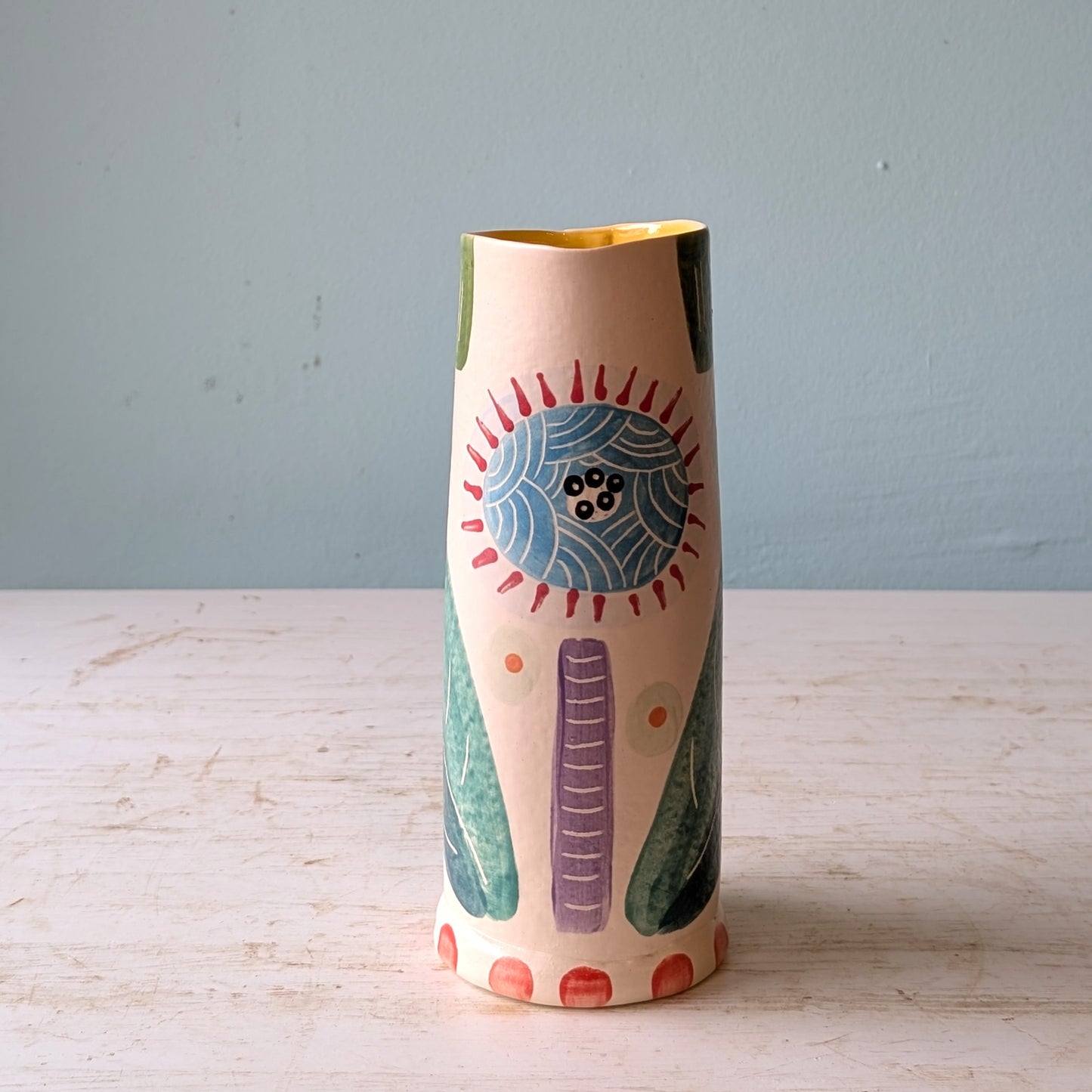 Decorative vase with abstract design on a wooden surface and light blue background
