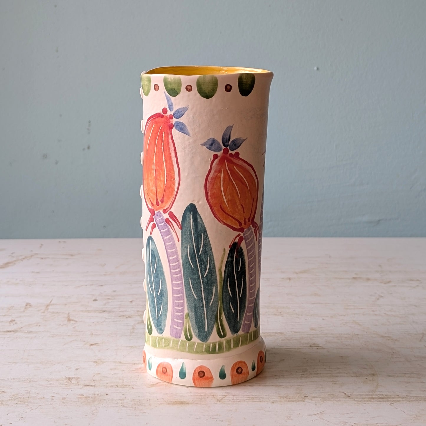 Decorative ceramic vase with floral patterns on a wooden surface and light blue background