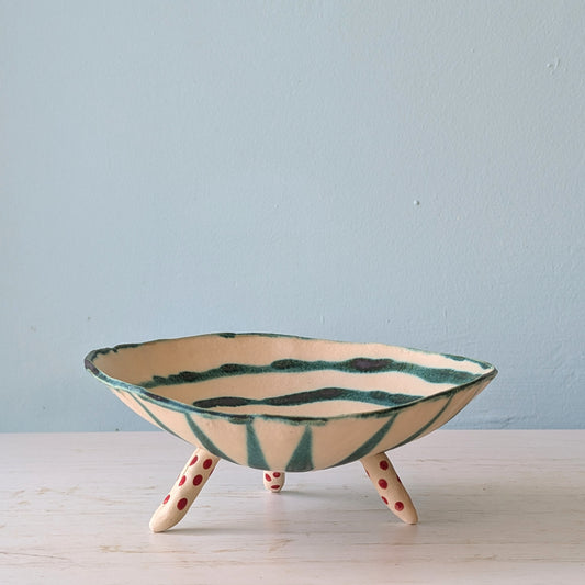 Ceramic bowl with green and beige design on a light blue background