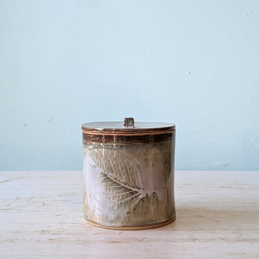 Ceramic jar with leaf design on a light blue background