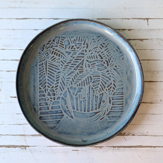 Top view of a blue/grey serving platter with a linocut poinsettia pattern