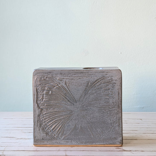 Front view of a grey/blue ceramic rectangular vase with a linocut butterfly pattern