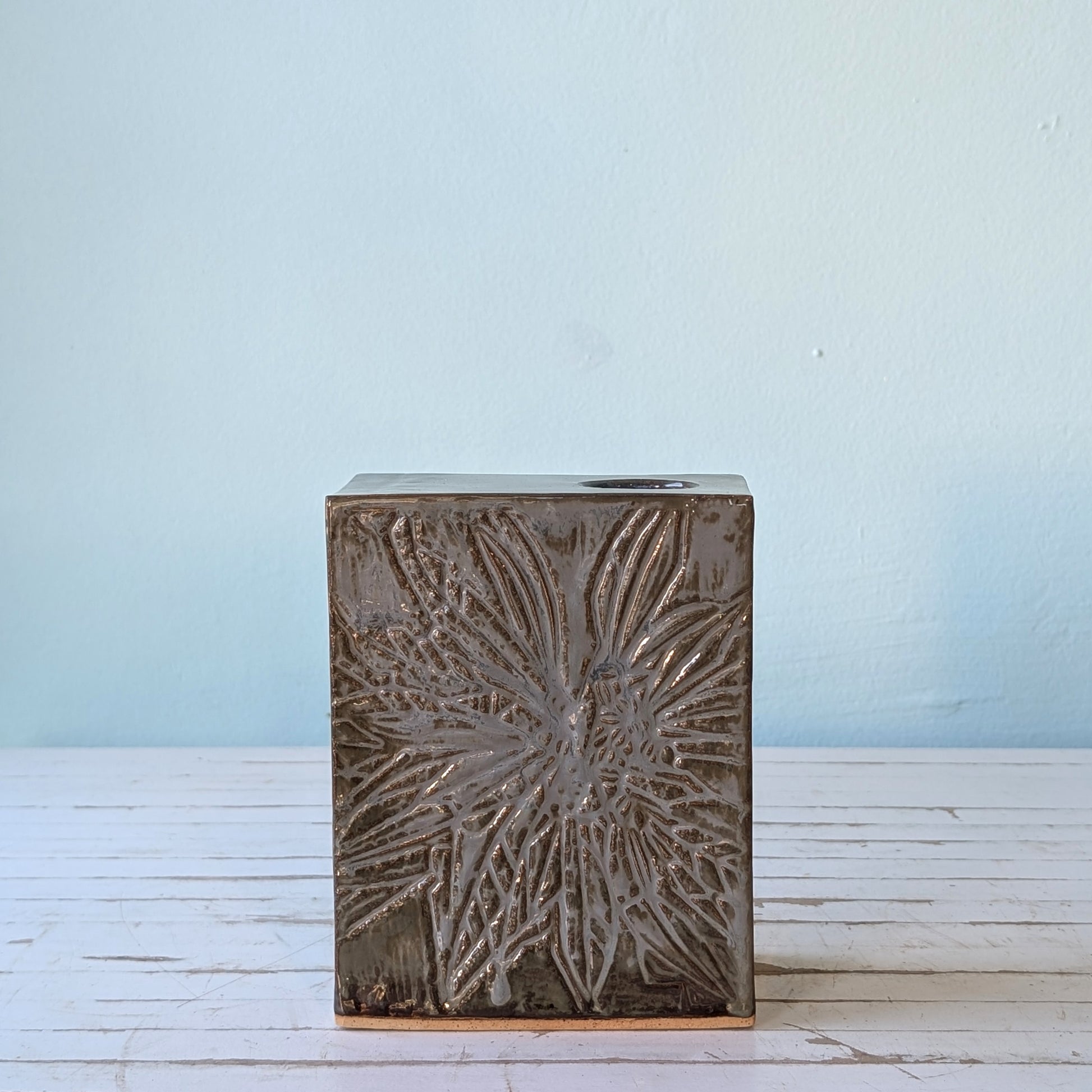Front view of a blue/grey ceramic rectangular vase with linocut flower pattern