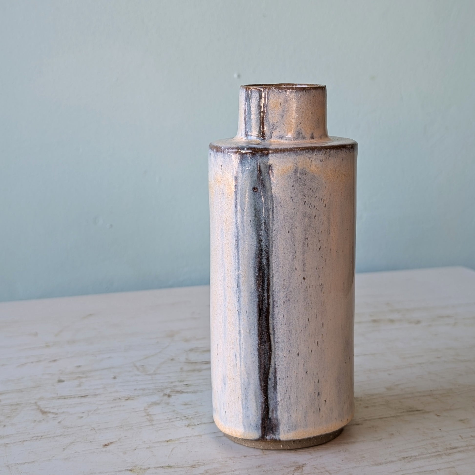 Ceramic vase on a light wooden surface with a light blue background