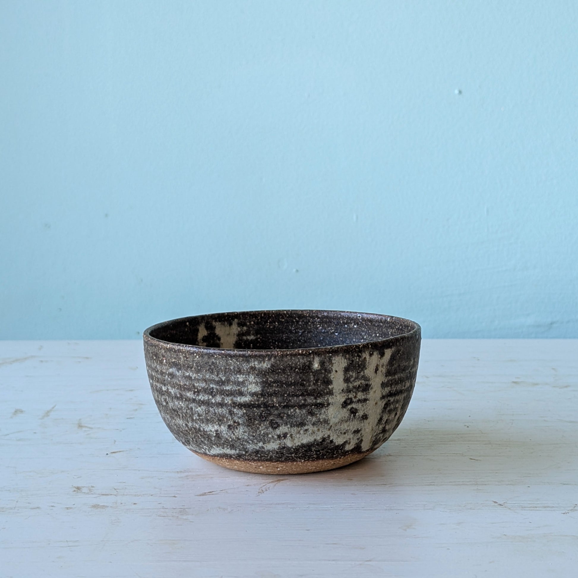 Ceramic bowl with speckled texture on a light blue background