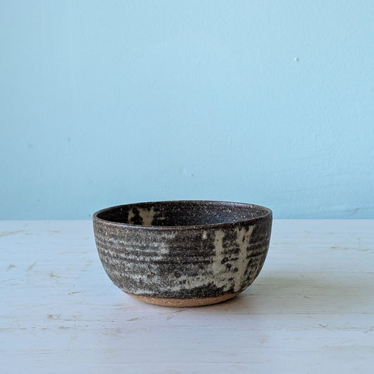 Ceramic bowl with speckled texture on a light blue background