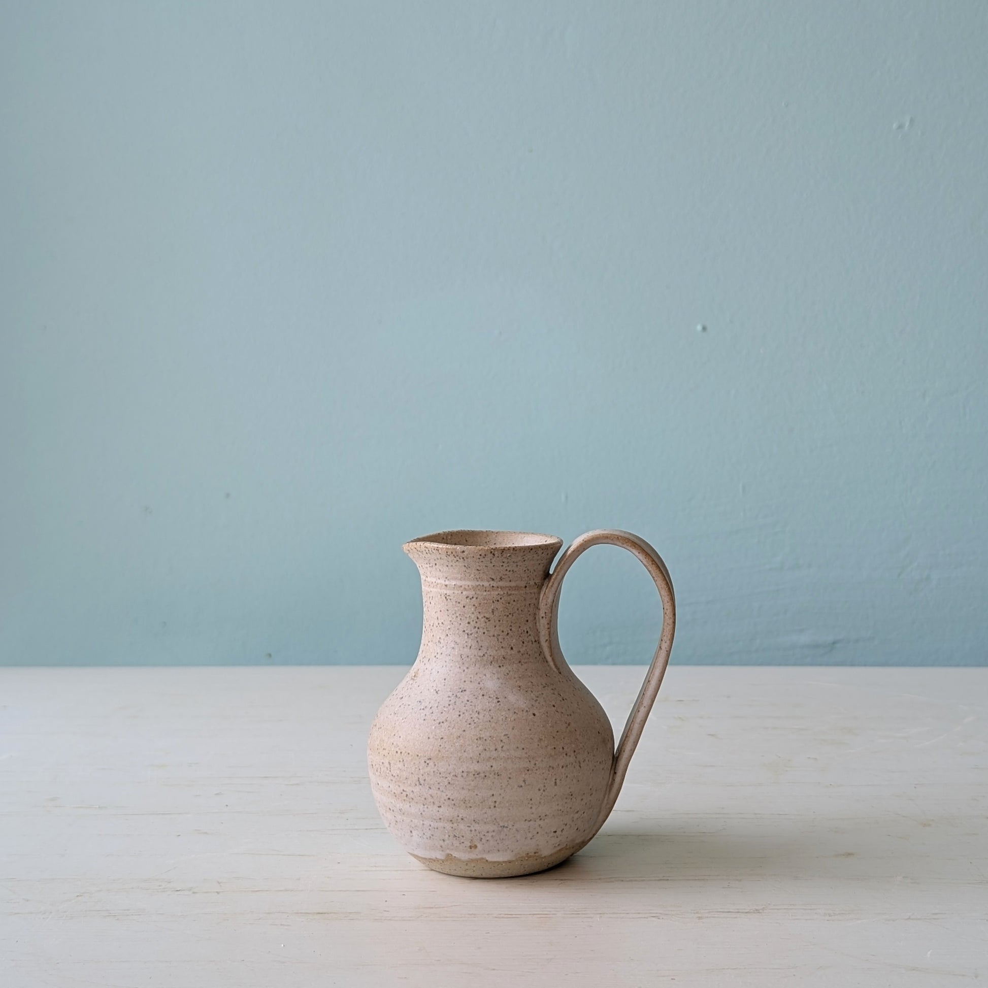 Beige ceramic pitcher on a light blue background