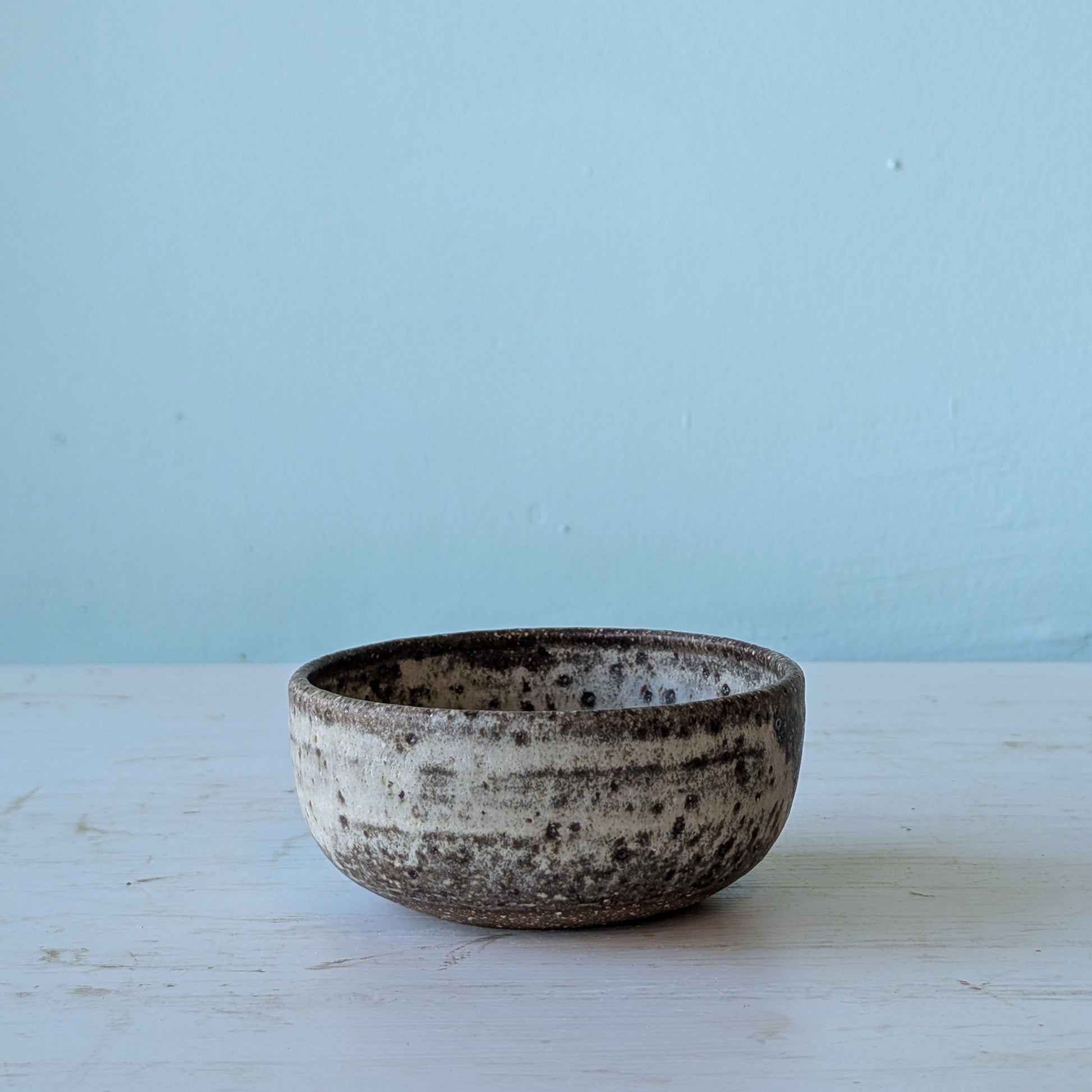 Ceramic bowl with speckled texture on a light blue background