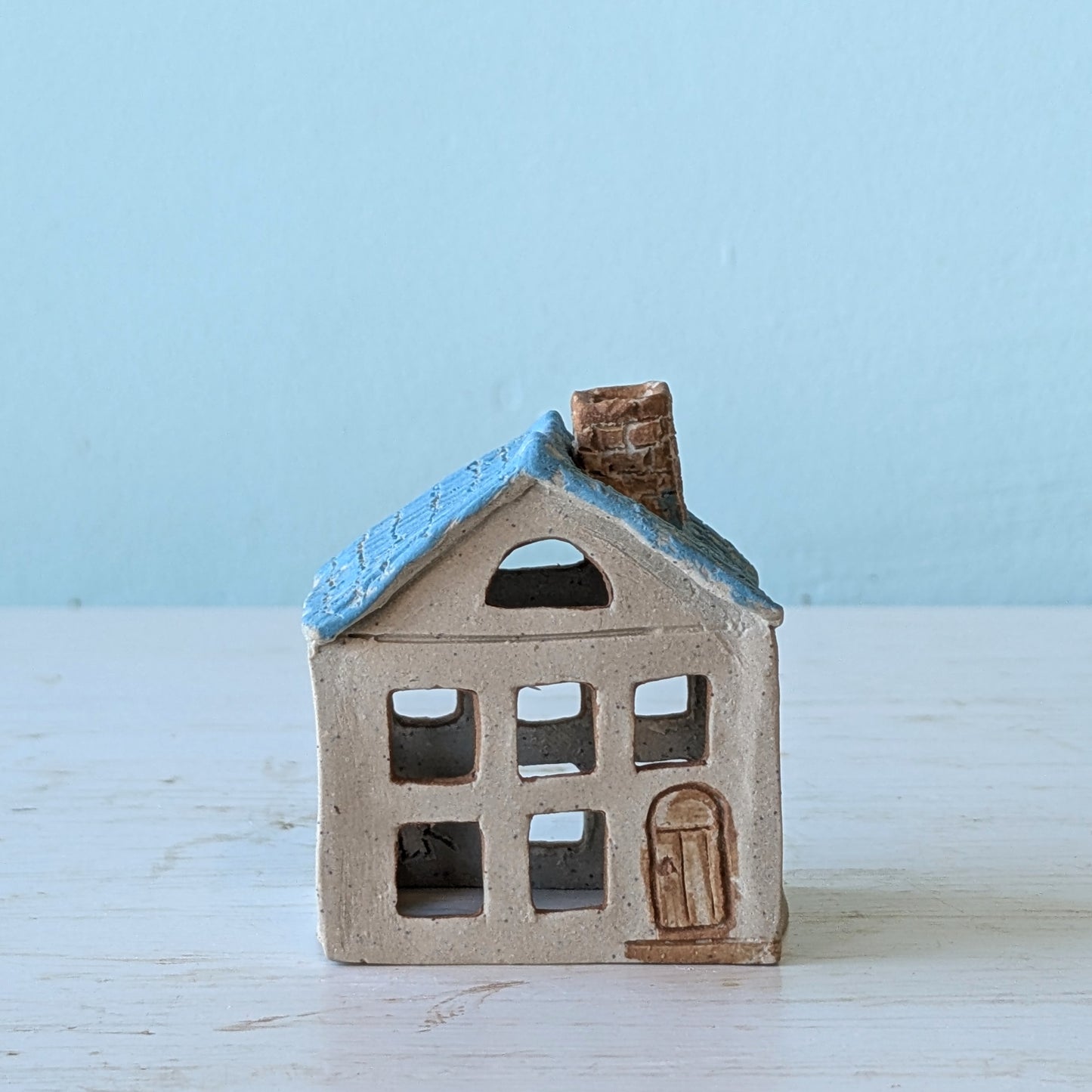 Small ceramic house figurine with blue roof