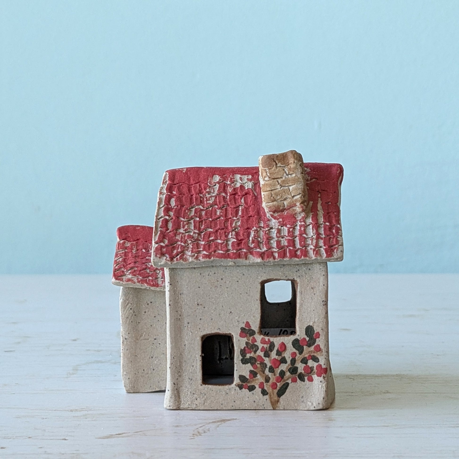 Ceramic house with a red roof on a light blue background
