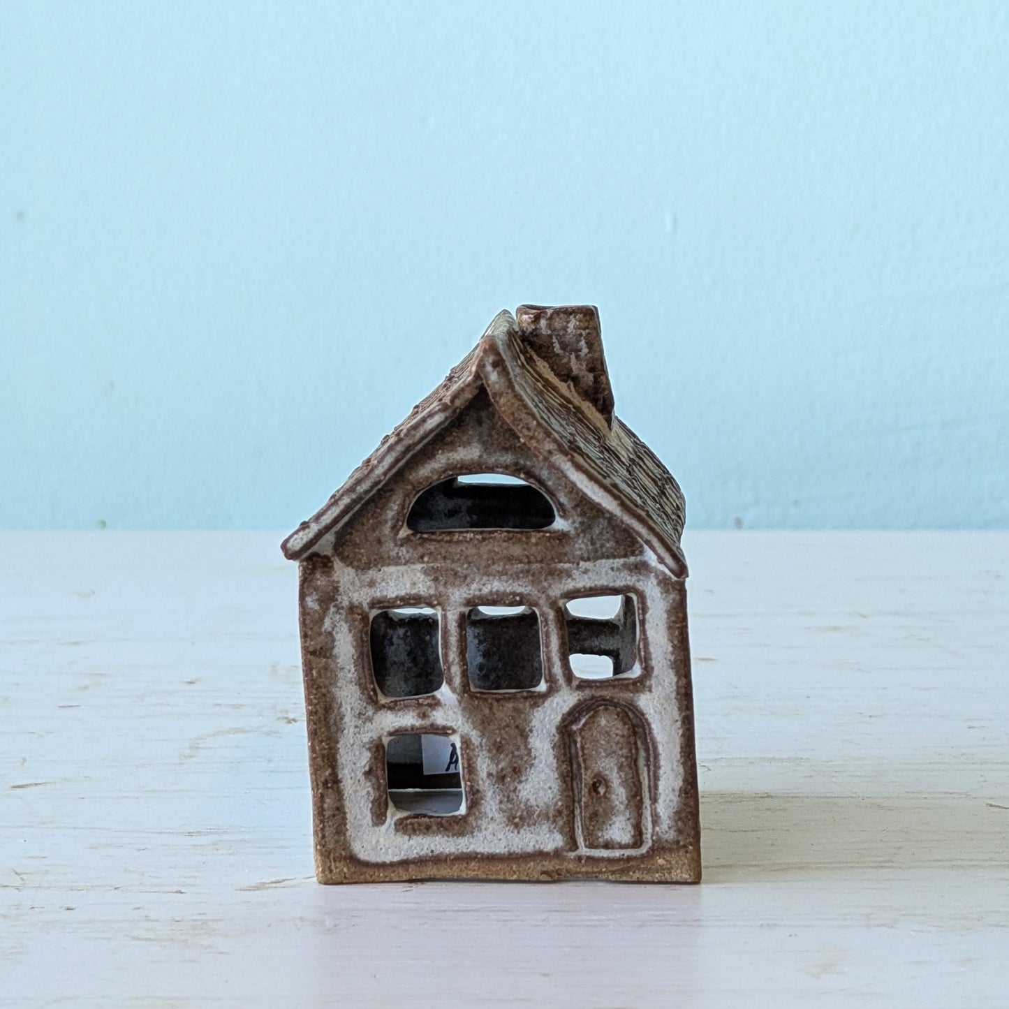 Ceramic house-shaped sculpture on a light blue background