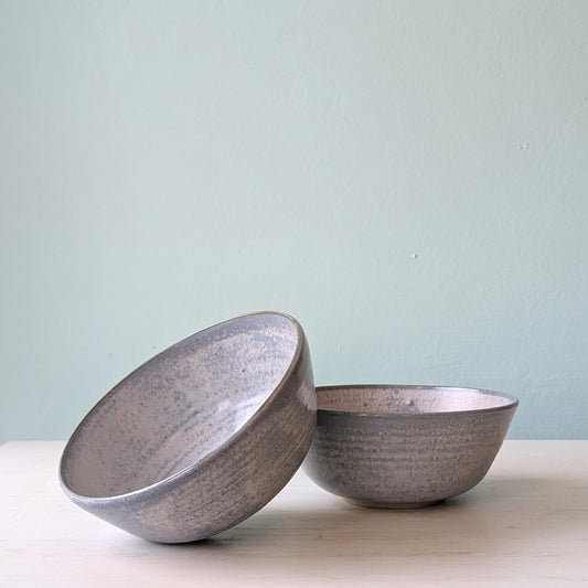 Two blue ceramic bowls on a light surface with a light blue background