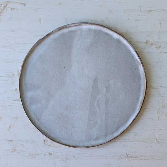 Round ceramic plate with a textured surface on a light wooden table