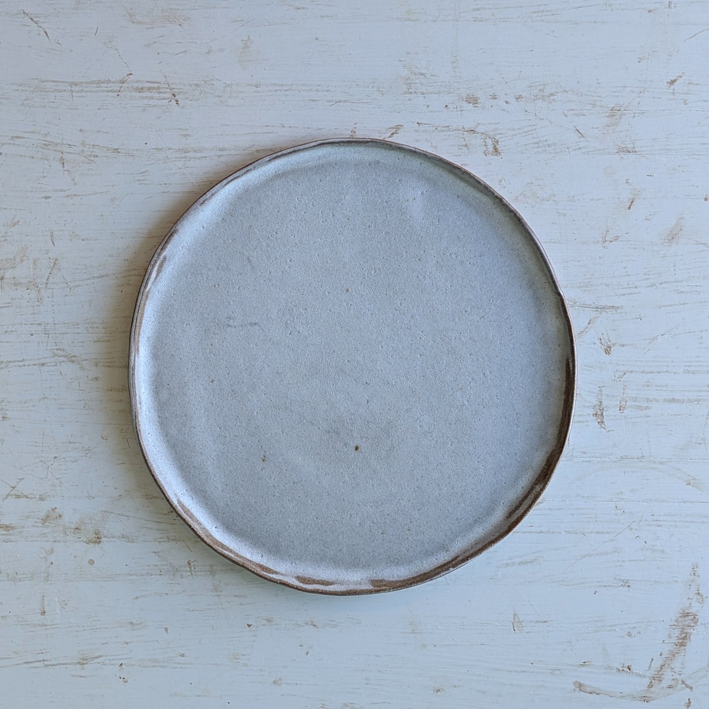 Round ceramic plate with a brown rim on a light blue wooden surface