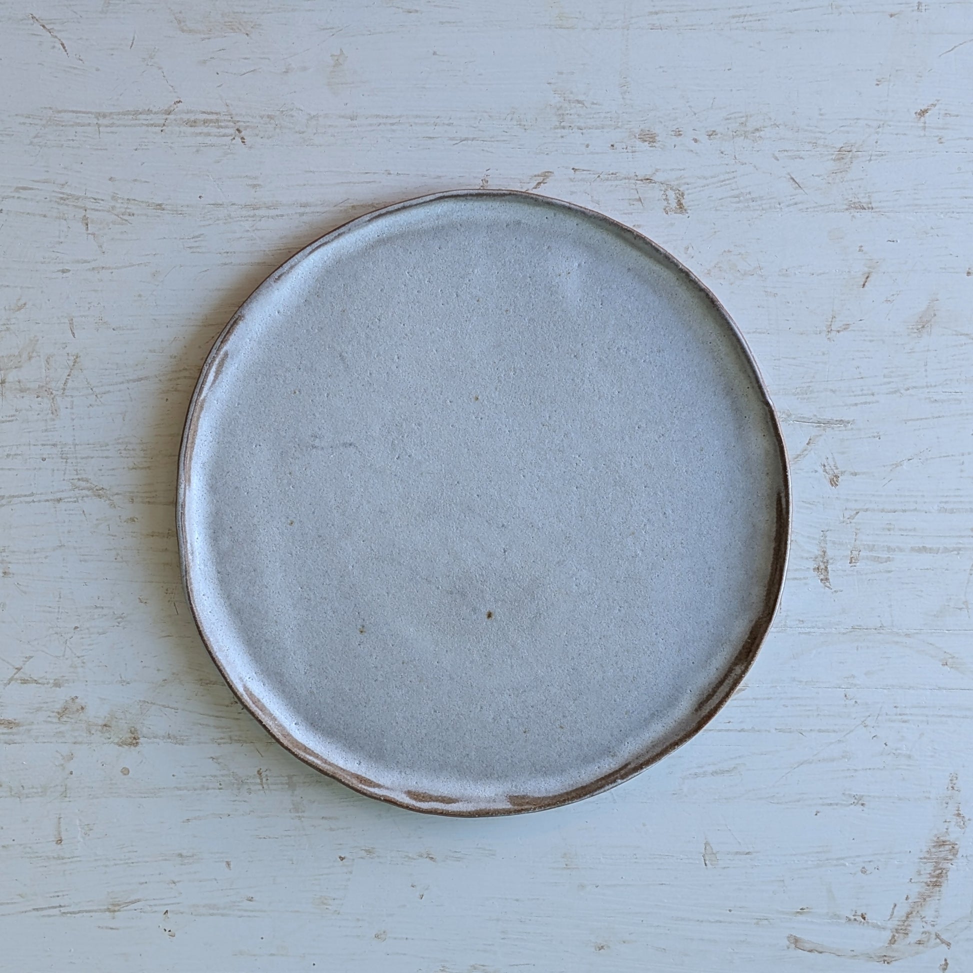 Round ceramic plate with a brown rim on a light blue wooden surface