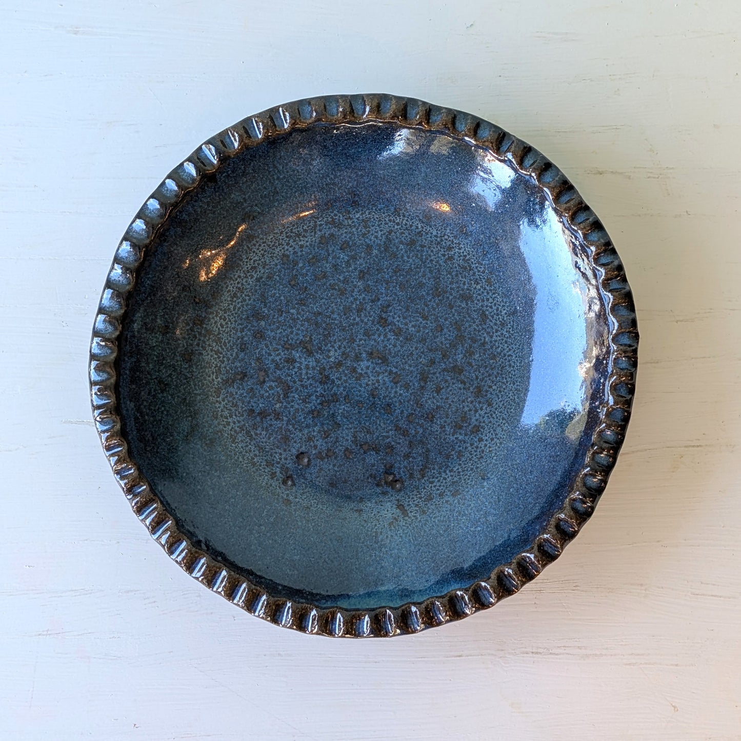 Blue ceramic plate with textured rim on a white background