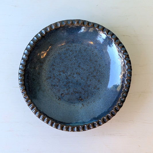 Blue ceramic plate with textured rim on a white background