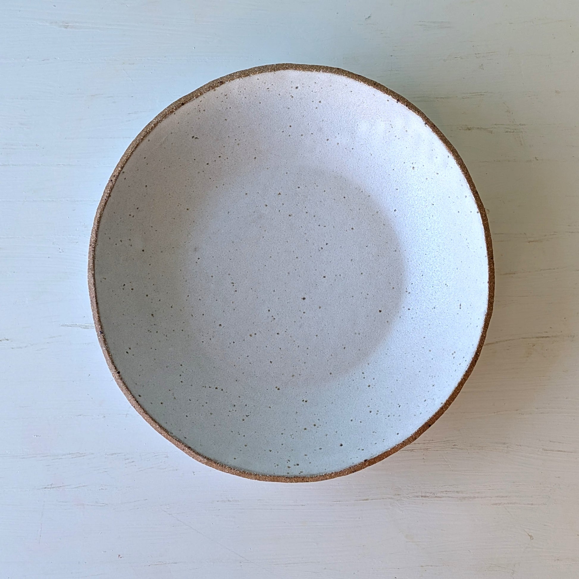 Ceramic bowl with speckled texture on a light wooden surface