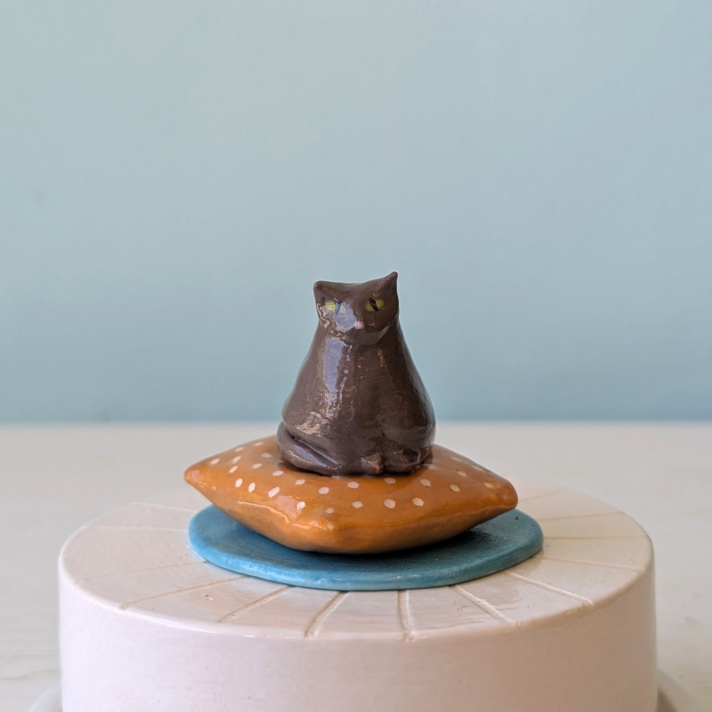 Ceramic cat figurine on a pillow with a blue background