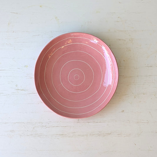 Pink ceramic plate with carved concentric circles on white table
