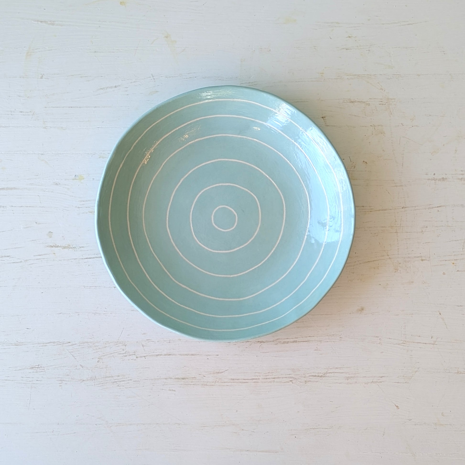Blue ceramic plate with  arved concentric circles on a white table