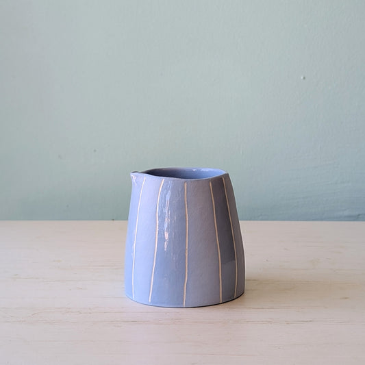 Small blue jug on a white table against a blue wall
