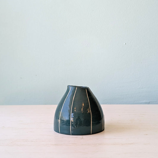 Dark green ceramic jug on white table against blue wall