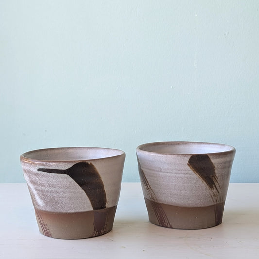 Two ceramic pots with brown and gray design on a light blue background