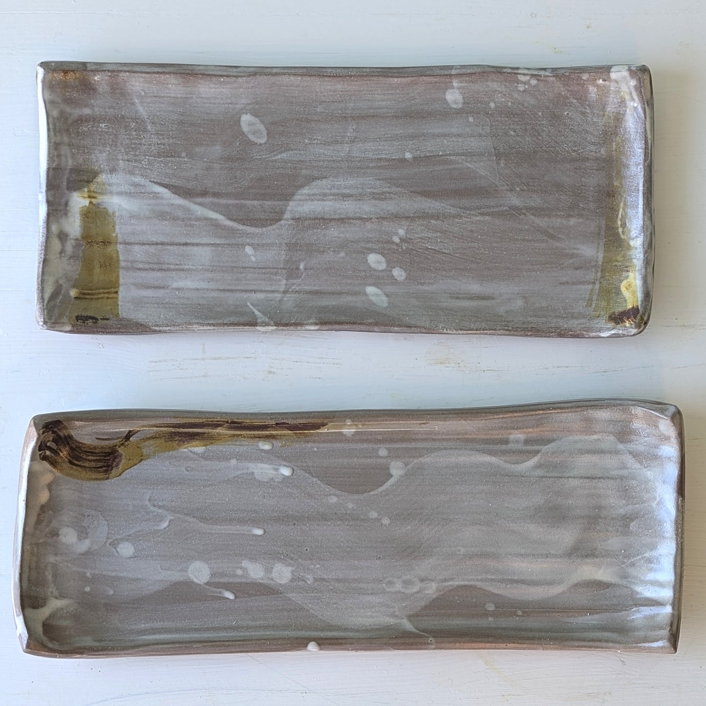 Two rectangular ceramic platters with an abstract design on a white background