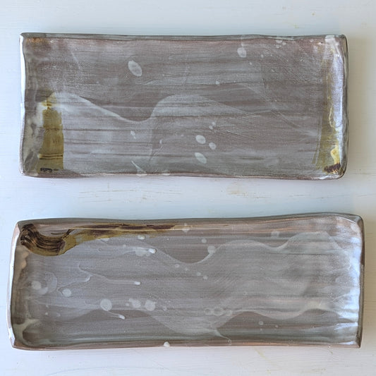 Two rectangular ceramic platters with an abstract design on a white background