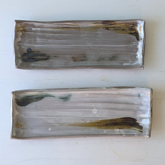 Two rectangular ceramic platters with abstract patterns on a white background