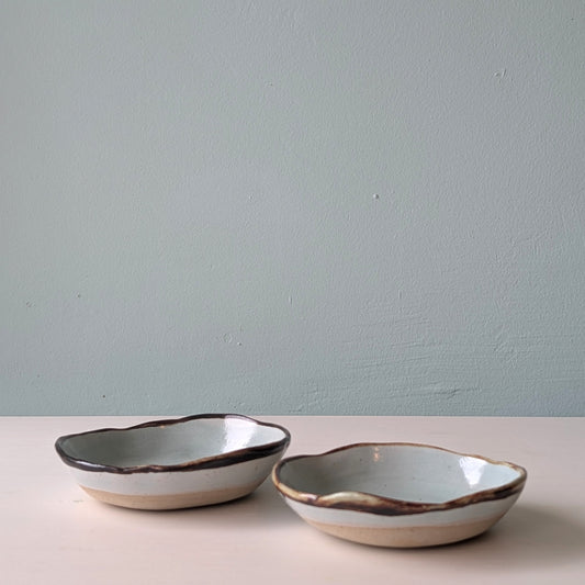 Two ceramic bowls with a rustic design on a light surface against a plain background