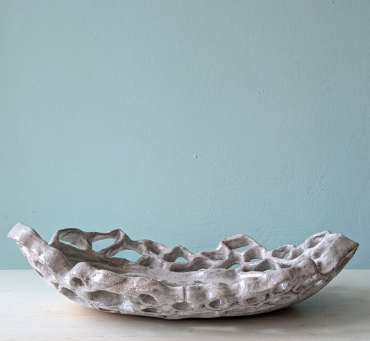 Decorative stoneware bowl on a light surface with a light blue wall background