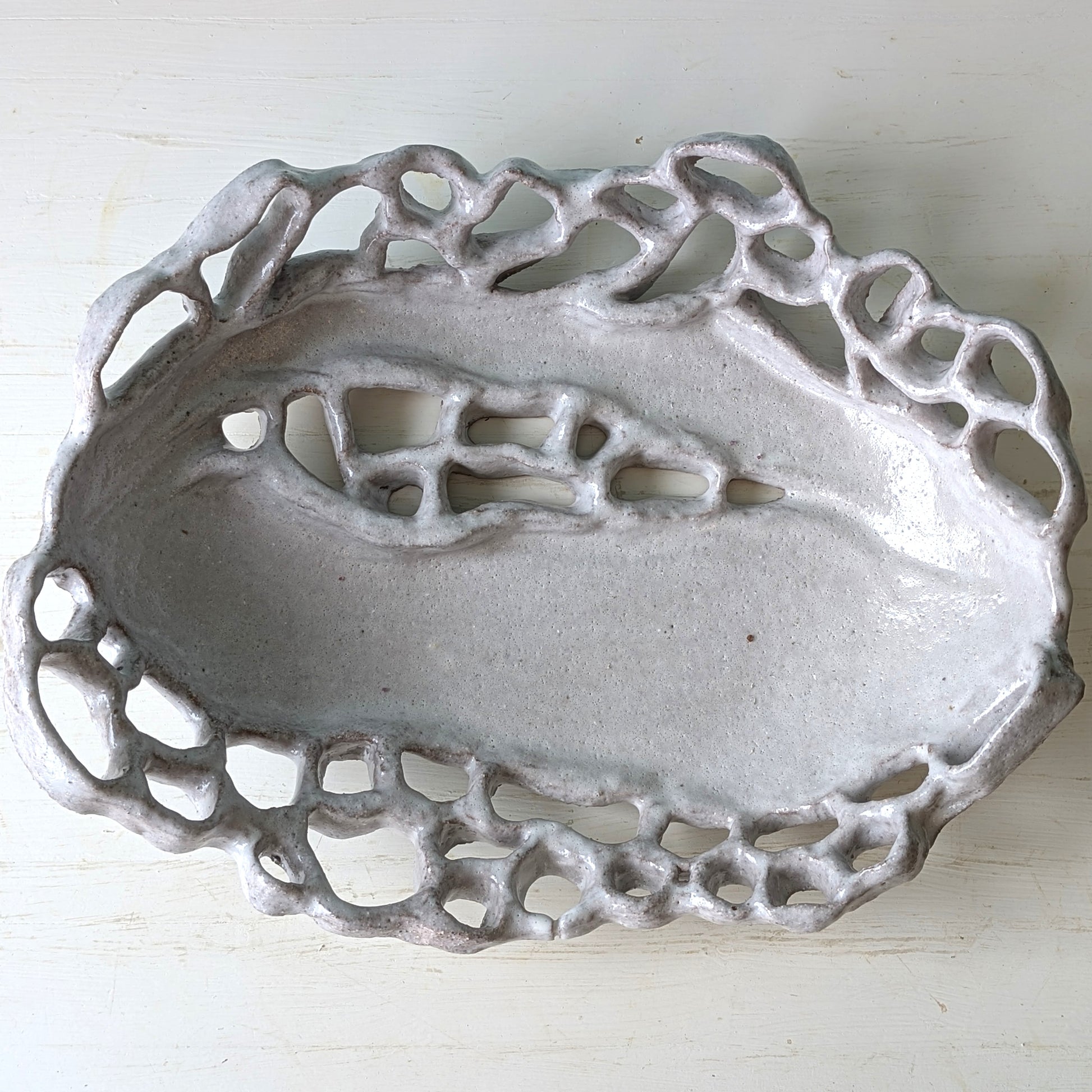 Decorative ceramic bowl with intricate lace-like pattern on a white background