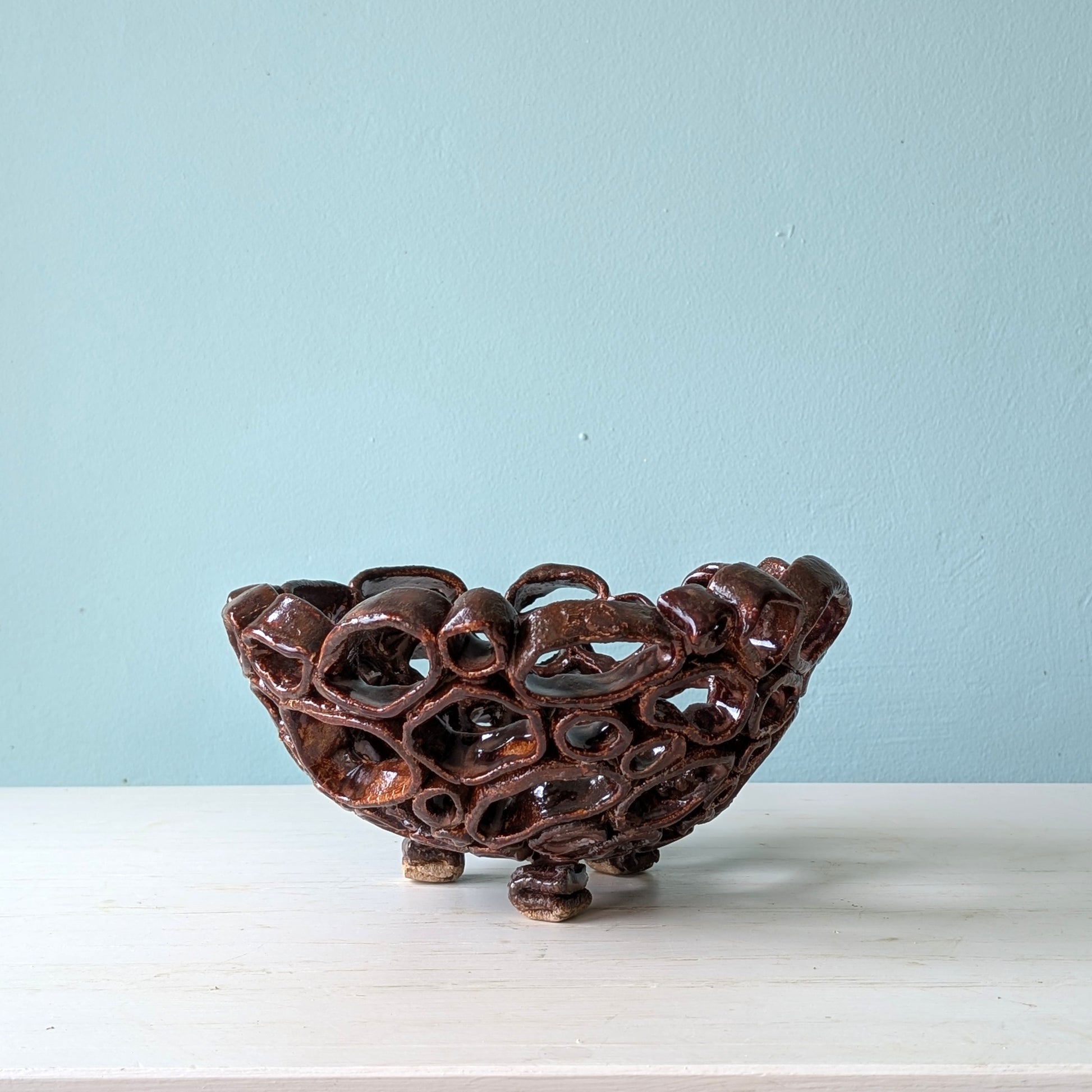 Brown ceramic bowl with intricate design on a white surface and light blue background