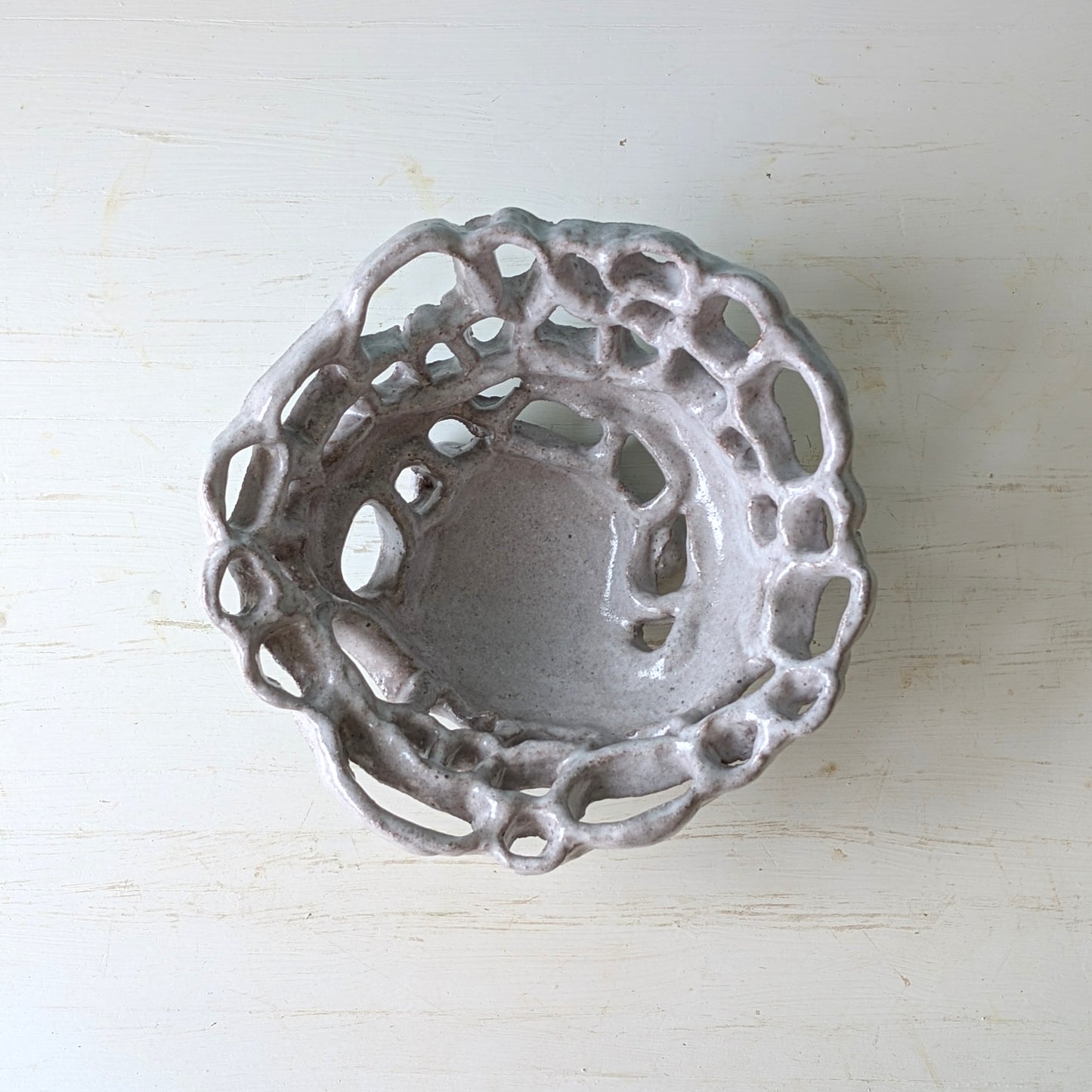 Decorative ceramic bowl with intricate lace-like design on a white background