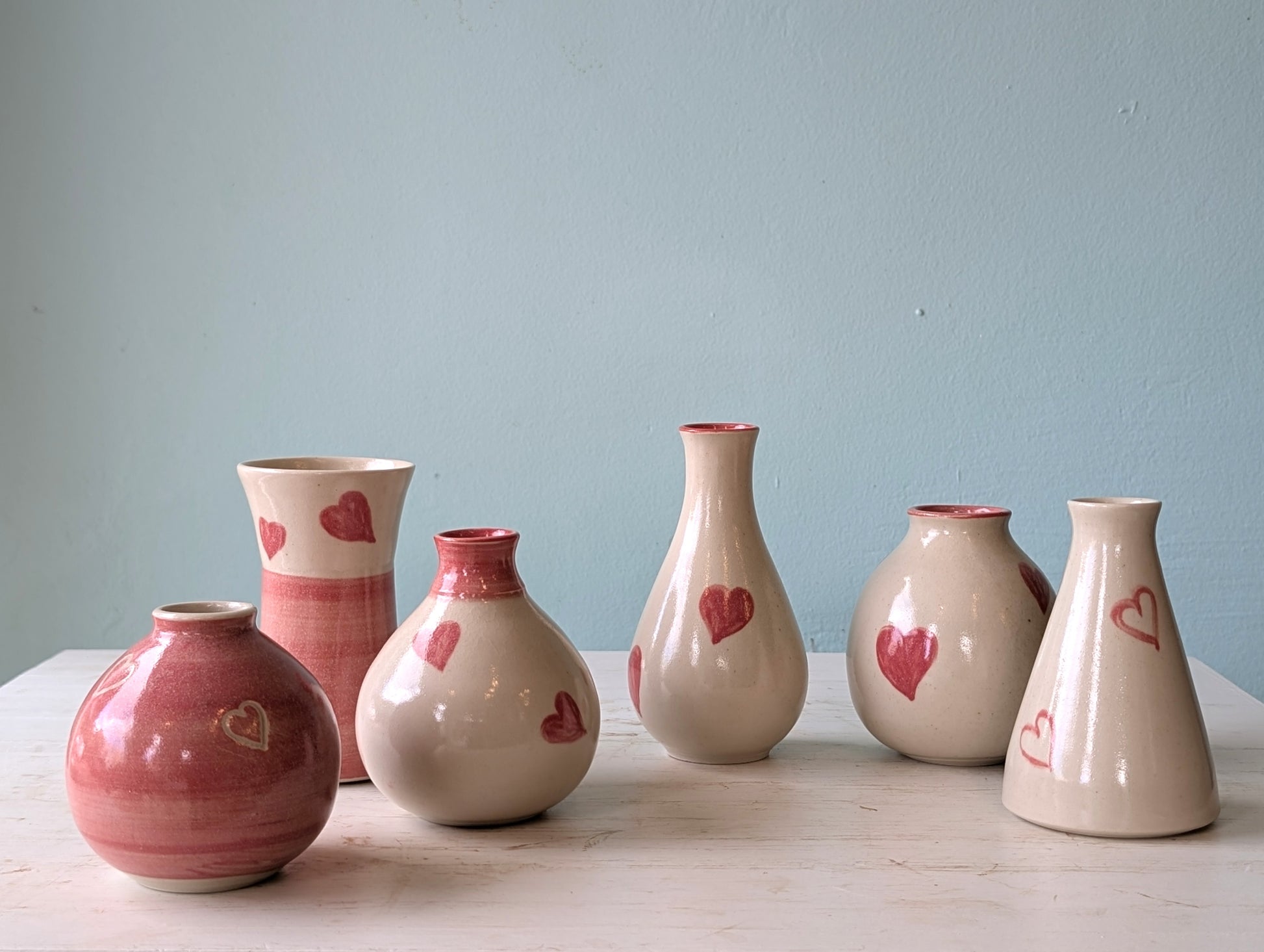 Set of ceramic vases with heart designs on a light blue background