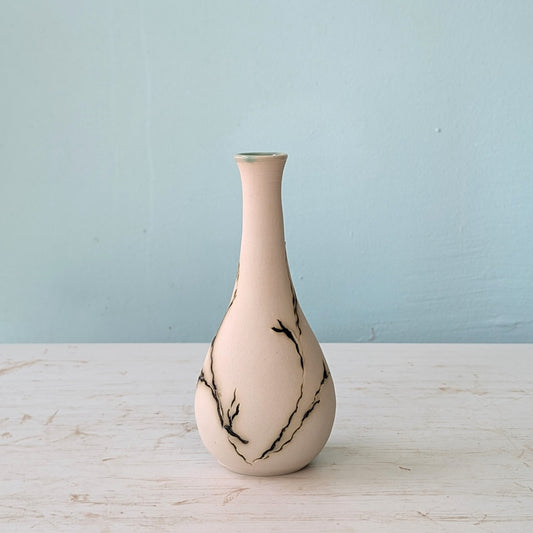 Seagrass-patterned vase on a wooden surface with a light blue background