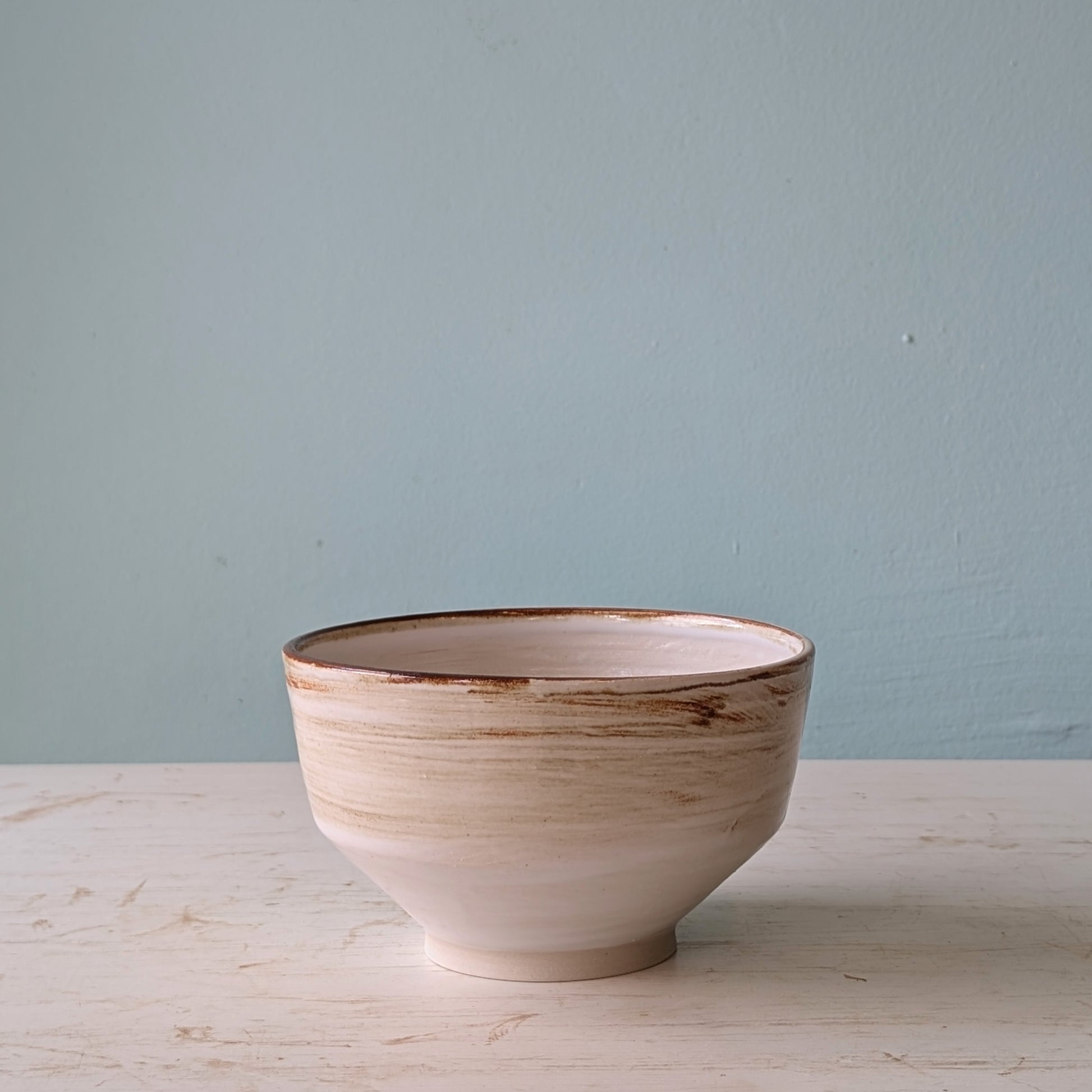 Ceramic bowl with a textured surface on a light wooden table against a light blue wall.