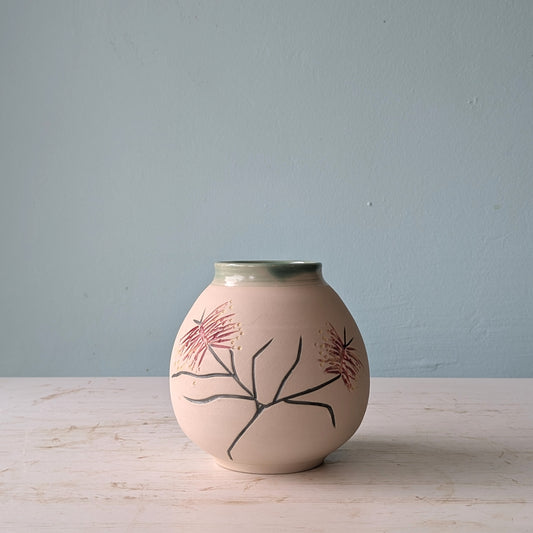 Ceramic vase with floral design on a light wooden surface and blue background